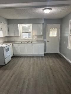 kitchen with a textured ceiling, dark hardwood / wood-style flooring, white range with electric stovetop, and white cabinets