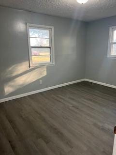 unfurnished room with dark wood-type flooring and a textured ceiling