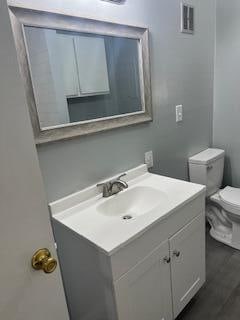 bathroom with toilet, hardwood / wood-style flooring, and vanity