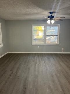 empty room with dark hardwood / wood-style flooring, a textured ceiling, and a wealth of natural light