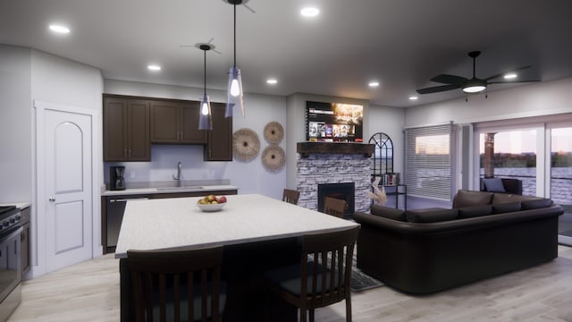 kitchen featuring dishwasher, a stone fireplace, light hardwood / wood-style flooring, decorative light fixtures, and ceiling fan