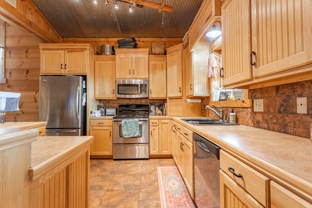 kitchen with wood walls, light brown cabinetry, appliances with stainless steel finishes, sink, and wood ceiling