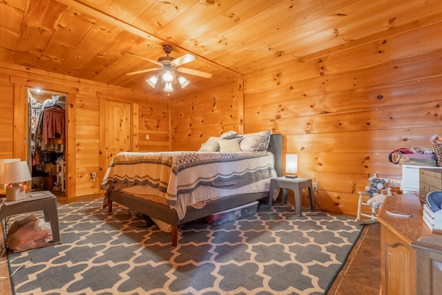 bedroom with a closet, wooden walls, wooden ceiling, a spacious closet, and ceiling fan