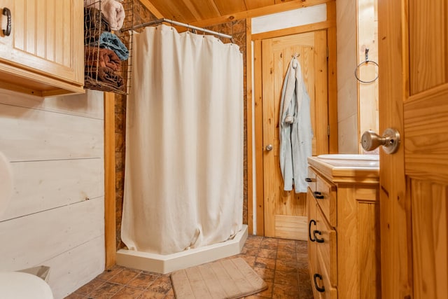 bathroom with vanity, wood walls, and curtained shower