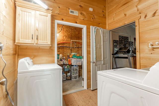 washroom featuring cabinets, light colored carpet, separate washer and dryer, and wood walls