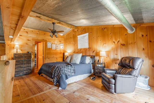 bedroom with ceiling fan, lofted ceiling with beams, wooden walls, and hardwood / wood-style floors