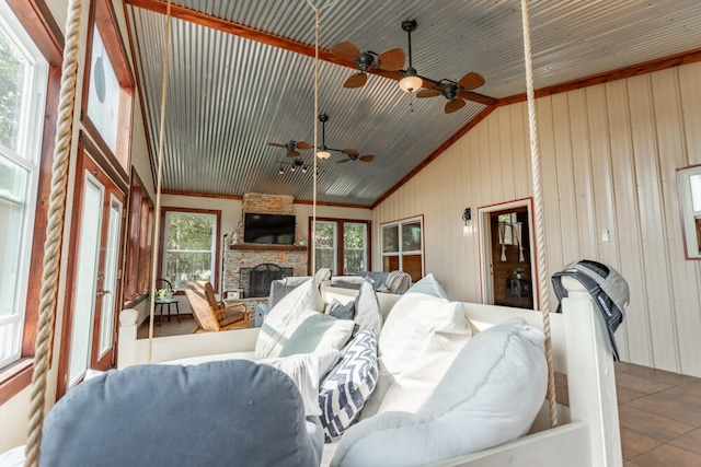 tiled living room with a wealth of natural light, a stone fireplace, high vaulted ceiling, and ceiling fan