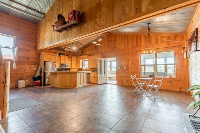 kitchen with a center island, stainless steel appliances, vaulted ceiling, and wooden walls