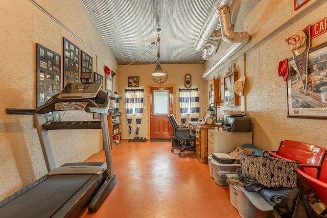 workout room with vaulted ceiling and concrete flooring