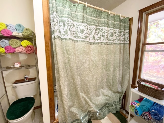 bathroom with toilet, a shower with curtain, and plenty of natural light