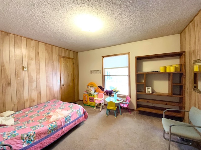 bedroom with wooden walls, a textured ceiling, and carpet flooring