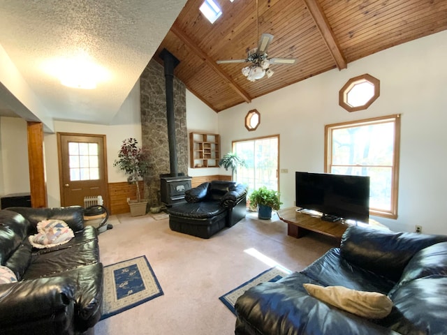 living room featuring a wealth of natural light, carpet, a wood stove, and wooden ceiling