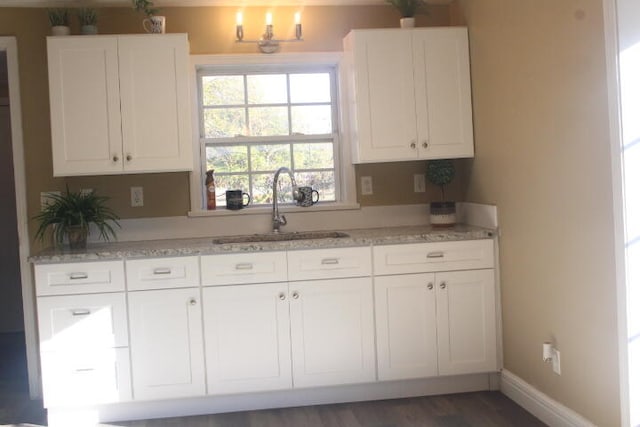 kitchen with white cabinetry, light stone countertops, sink, and dark wood-type flooring