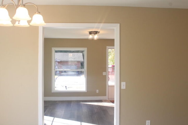 doorway to outside with wood-type flooring and an inviting chandelier