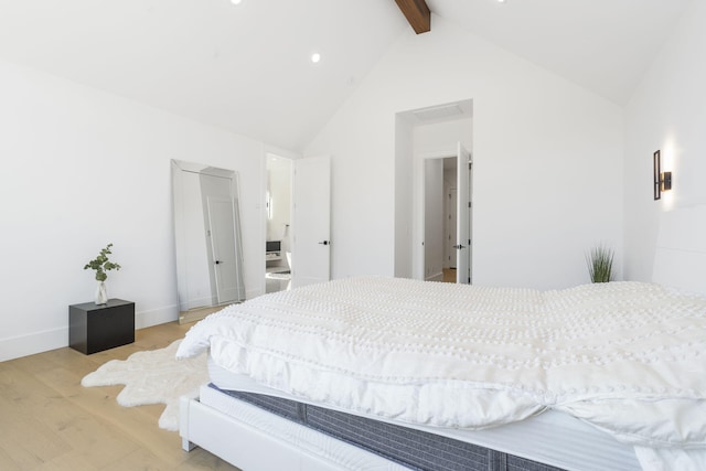 bedroom featuring vaulted ceiling with beams and light wood-type flooring