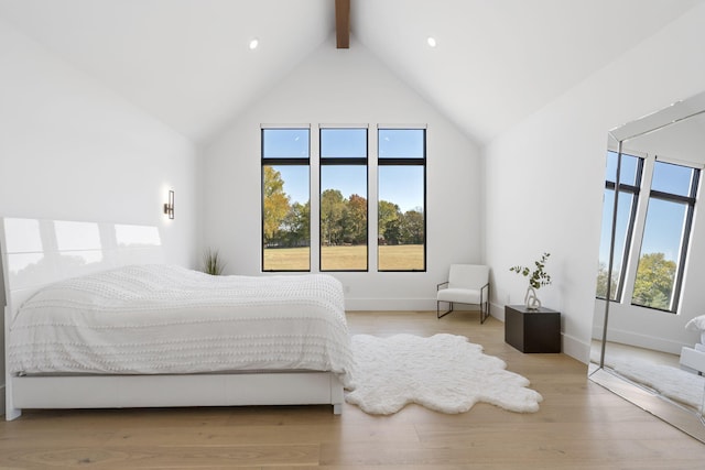 bedroom with beam ceiling, high vaulted ceiling, and light wood-type flooring