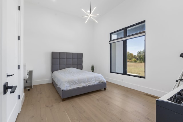 bedroom featuring an inviting chandelier and light wood-type flooring