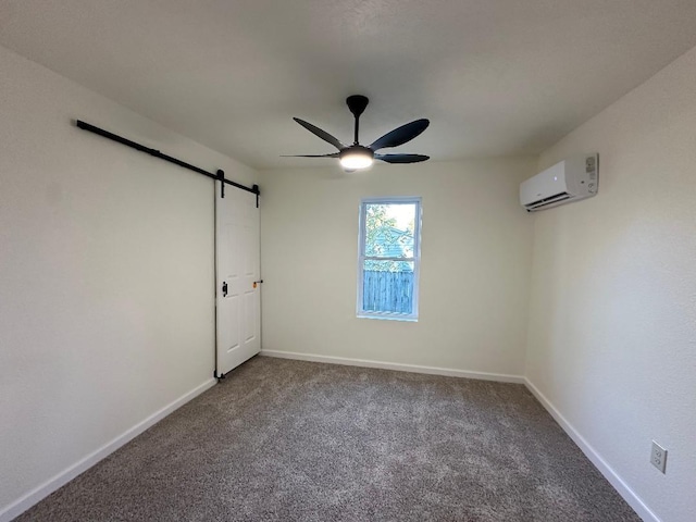 carpeted spare room featuring a barn door, a wall unit AC, and ceiling fan