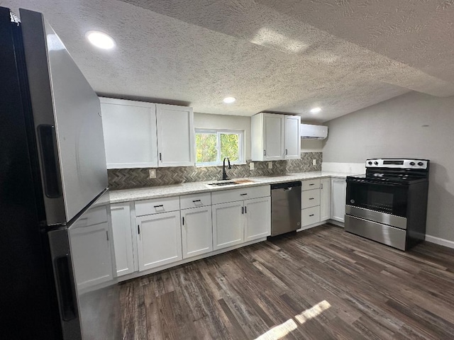 kitchen featuring appliances with stainless steel finishes, sink, a textured ceiling, white cabinetry, and dark wood-type flooring