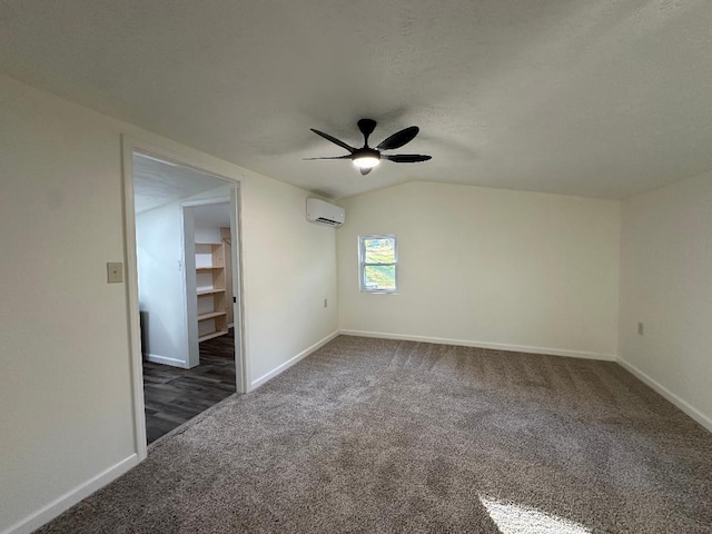 carpeted empty room featuring lofted ceiling, a wall unit AC, a textured ceiling, and ceiling fan