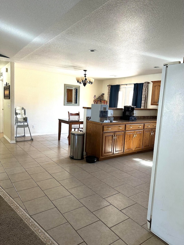 kitchen with a notable chandelier, a textured ceiling, white fridge, and light tile patterned flooring