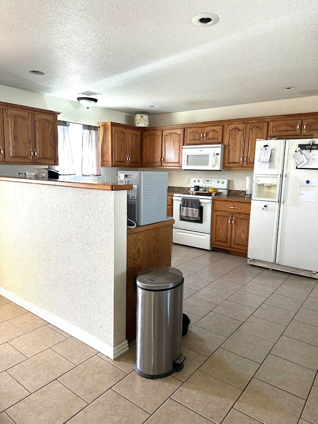 kitchen featuring a textured ceiling, light tile patterned flooring, and white appliances