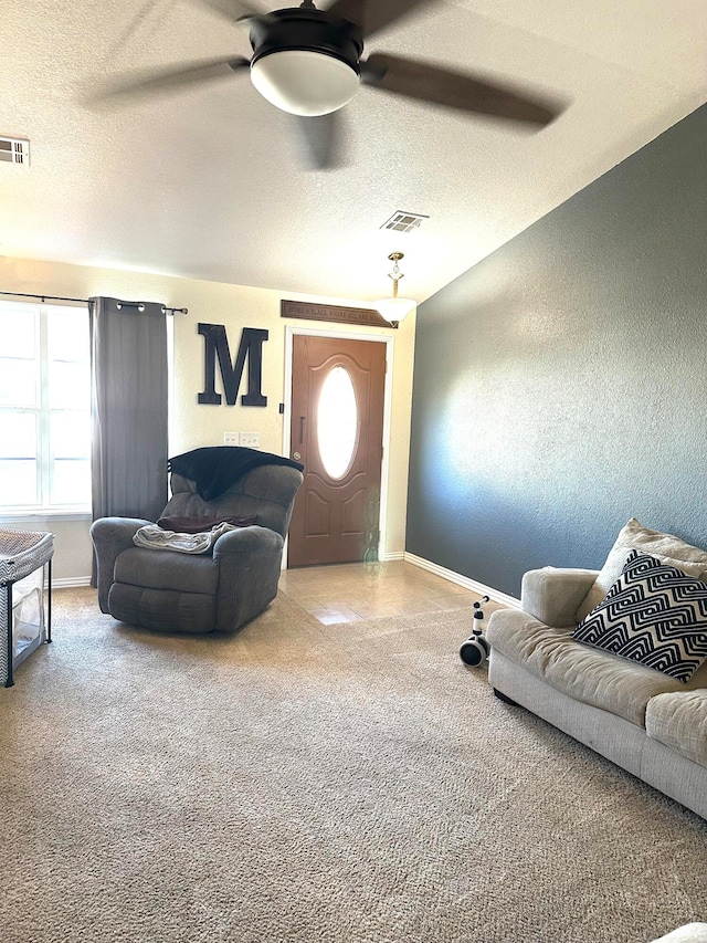 carpeted living room with a wealth of natural light, a textured ceiling, and ceiling fan