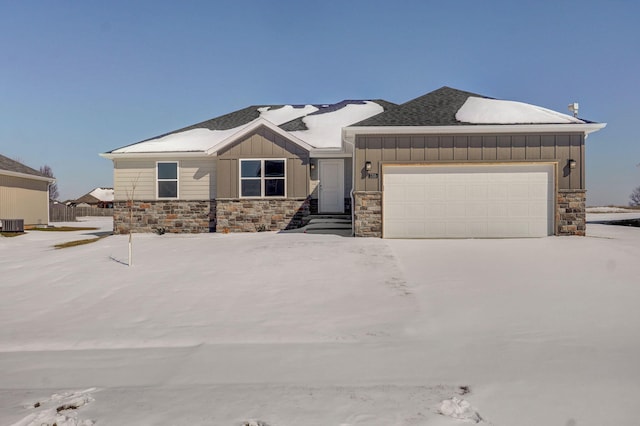 view of front of property featuring a garage, central AC, driveway, stone siding, and board and batten siding