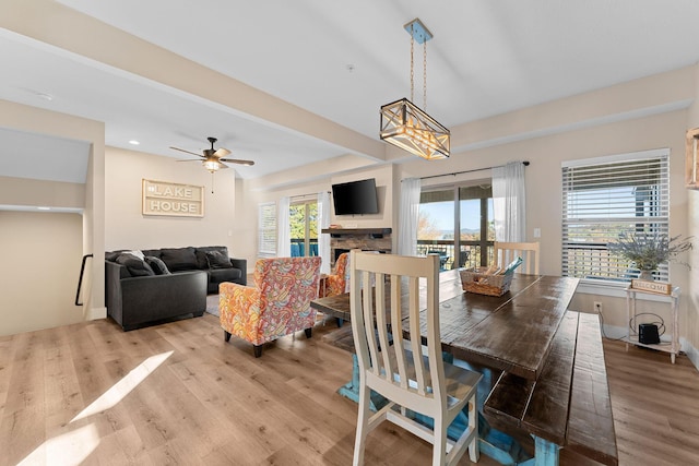 dining room with light wood finished floors, ceiling fan, and a fireplace