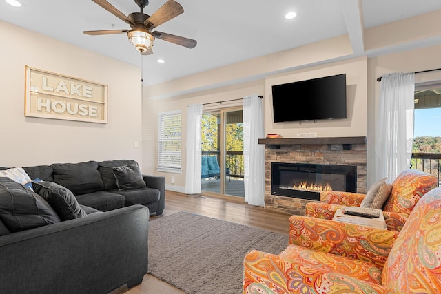 living area with recessed lighting, ceiling fan, a stone fireplace, and wood finished floors