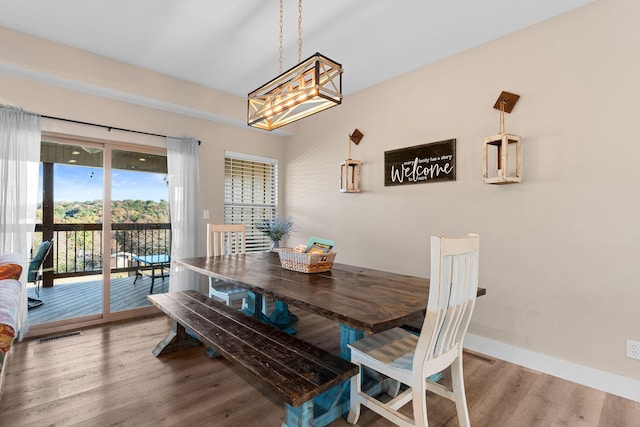 dining space featuring visible vents, wood finished floors, a notable chandelier, and baseboards