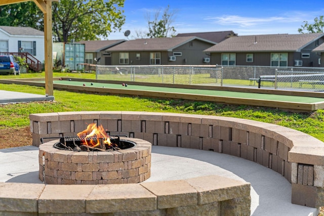 view of patio featuring an outdoor fire pit, fence, and a residential view