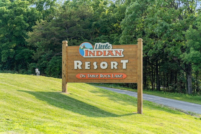 community sign featuring a yard and a forest view