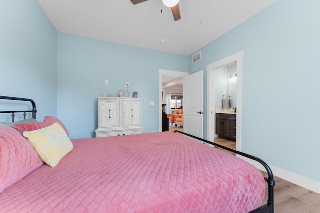 bedroom with a ceiling fan, visible vents, baseboards, wood finished floors, and ensuite bathroom