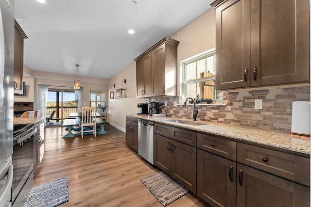kitchen featuring light wood-style flooring, stainless steel appliances, decorative backsplash, and a sink