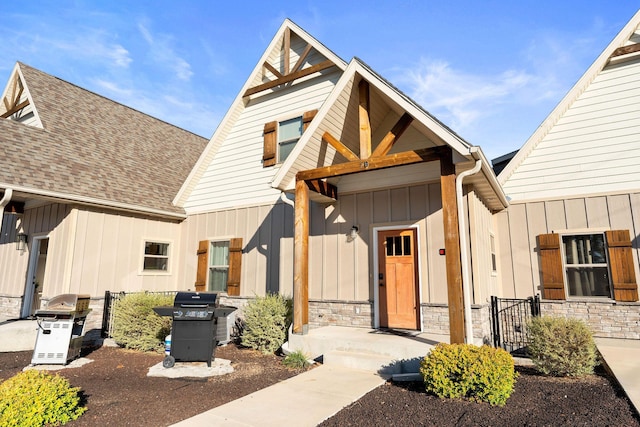 view of front facade featuring stone siding, board and batten siding, and a shingled roof