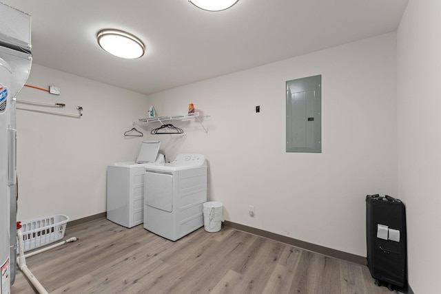 laundry area with laundry area, light wood-style flooring, washing machine and clothes dryer, electric panel, and baseboards