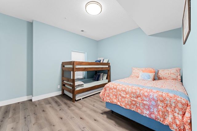 bedroom with wood finished floors, visible vents, and baseboards