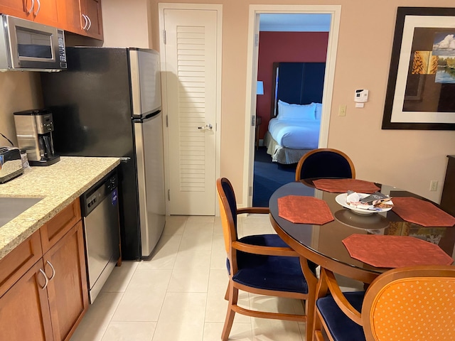 kitchen featuring light stone counters, stainless steel appliances, and light tile patterned floors