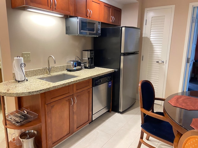 kitchen featuring appliances with stainless steel finishes, sink, light stone counters, and light tile patterned floors