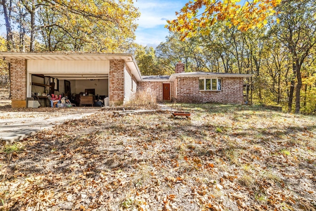 view of front of house with brick siding, an attached garage, and a chimney