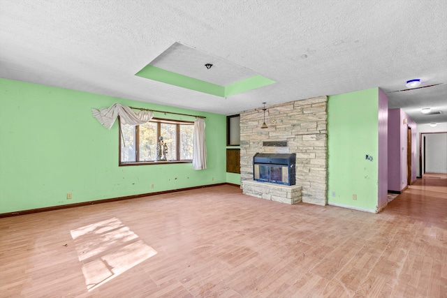 unfurnished living room featuring baseboards, a textured ceiling, wood finished floors, and a fireplace
