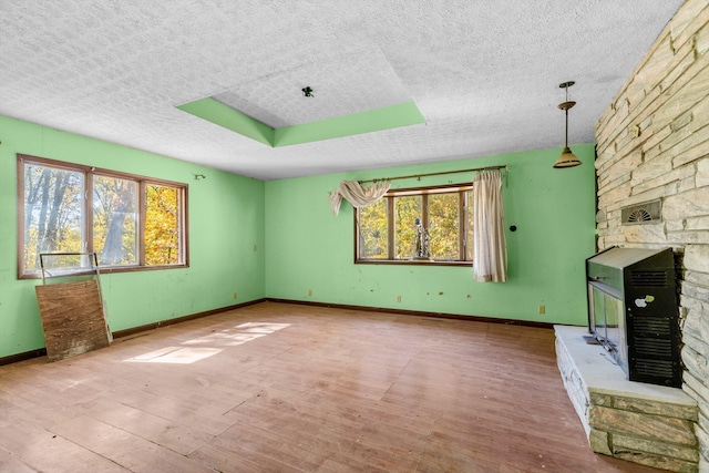 unfurnished living room with a textured ceiling, baseboards, a fireplace, and wood finished floors
