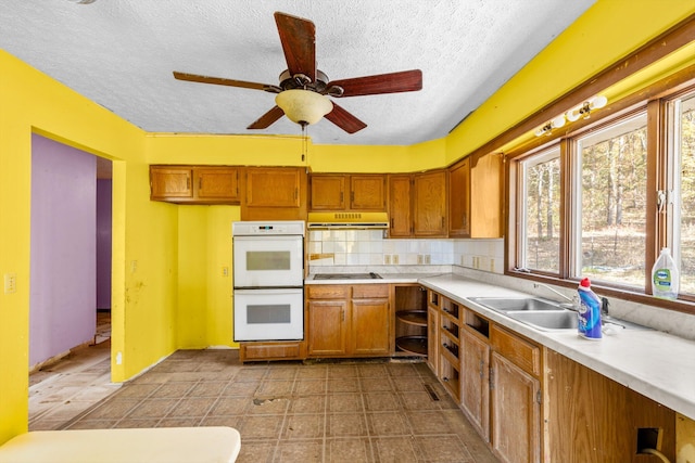 kitchen featuring brown cabinets, a textured ceiling, white double oven, and a wealth of natural light