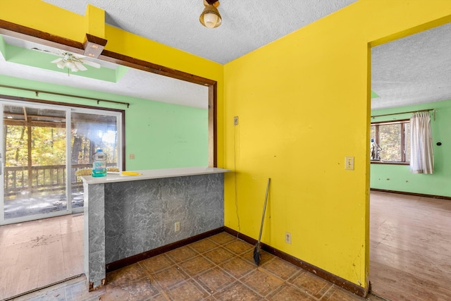 unfurnished room with baseboards, ceiling fan, and a textured ceiling