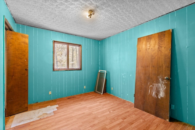 spare room with a textured ceiling and wood finished floors