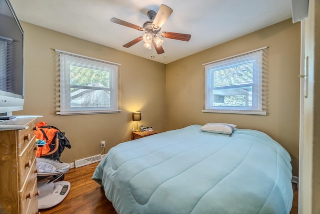 bedroom featuring dark hardwood / wood-style flooring, multiple windows, and ceiling fan