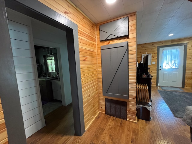 mudroom featuring hardwood / wood-style floors, a barn door, and wood walls