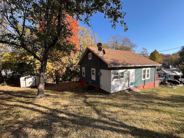 exterior space featuring a yard, a shed, and cooling unit