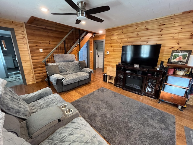 living room featuring ceiling fan, hardwood / wood-style flooring, and wooden walls